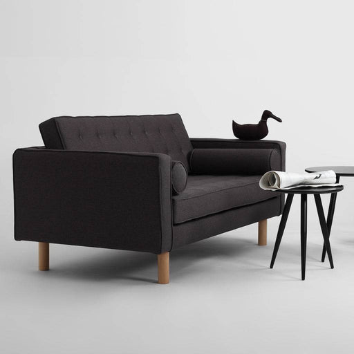 Divano in tessuto nero con schienale inclinato, gambe in legno chiaro, stile minimalista, ambientazione con oggetti decorativi, SKU: SF025TOPW2-ET95