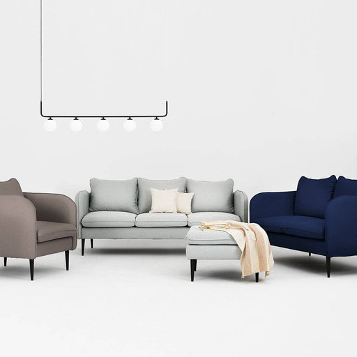 Immagine di un soggiorno con divani colorati in tessuto, tra cui un divano in nero inchiostro, stile minimalista e atmosfera luminosa.