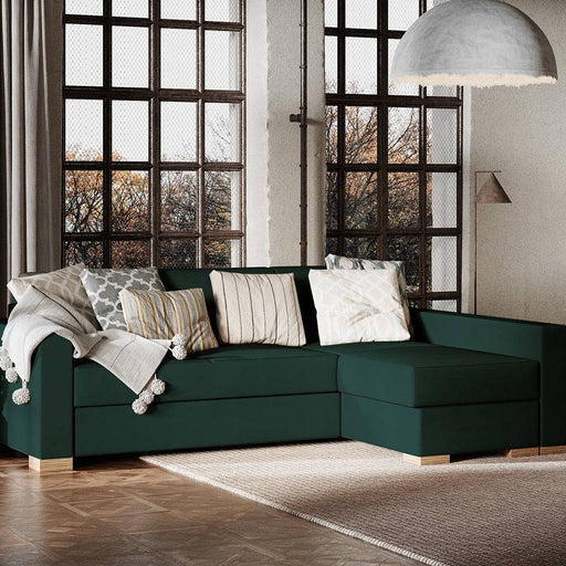 Soggiorno con divano angolare verde scuro, ampio e confortevole, decorato con cuscini, grande finestra e illuminazione naturale