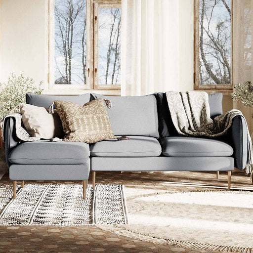 Interno con divano in tessuto grigio chiaro, decorato con cuscini e tappeti, ambiente luminoso e accogliente
