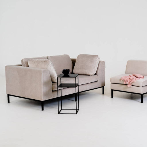 Divano in tessuto beige chiaro con struttura in metallo nero, con cuscini e poltrona coordinata, ambiente luminoso e raffinato