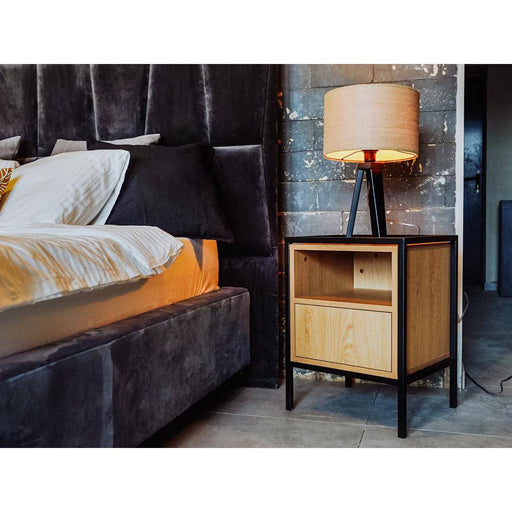Comodino in legno chiaro con lampada da tavolo, ideale come mobile da notte in ambienti contemporanei e accoglienti.