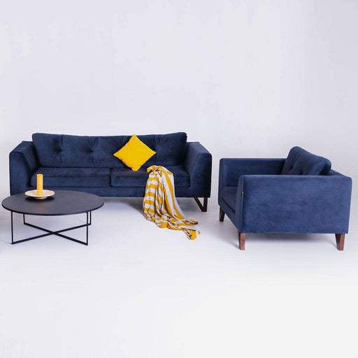 Divano in velluto blu con cuscino giallo e coperta a righe gialle e bianche, stile contemporaneo con tavolino nero e decorazioni colorate