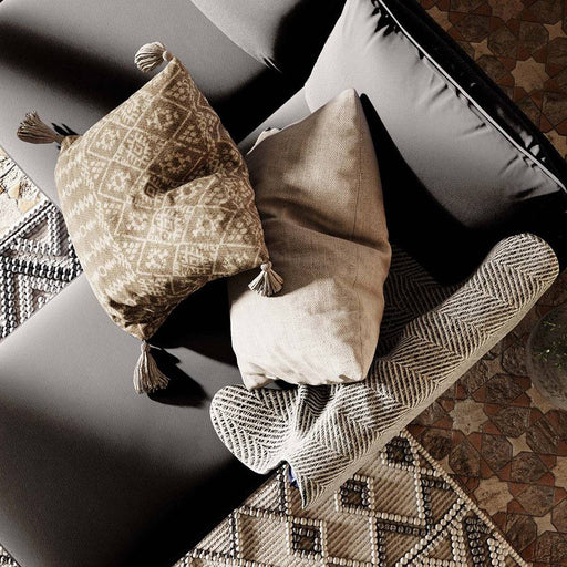 Immagine di un divano con cuscini decorativi in tessuto beige e nero, rivestimento in pelle nera, perfetto per ambienti eleganti e accoglienti