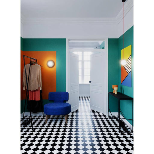Interno di un ingresso con pareti colorate, pavimento a scacchi e console nera con seduta blu, stile moderno e vivace