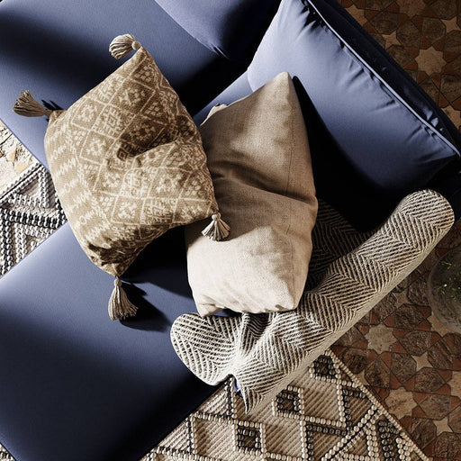 Dettaglio del divano con cuscini decorativi beige e marroni, rivestimento in tessuto blu scuro, perfetto per ambienti eleganti.