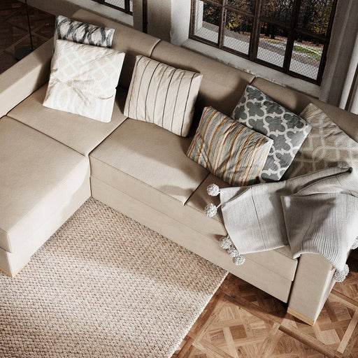 Divano beige con cuscini decorativi in tessuto con motivi geometrici e linee morbide, perfetto per ambienti eleganti e accoglienti