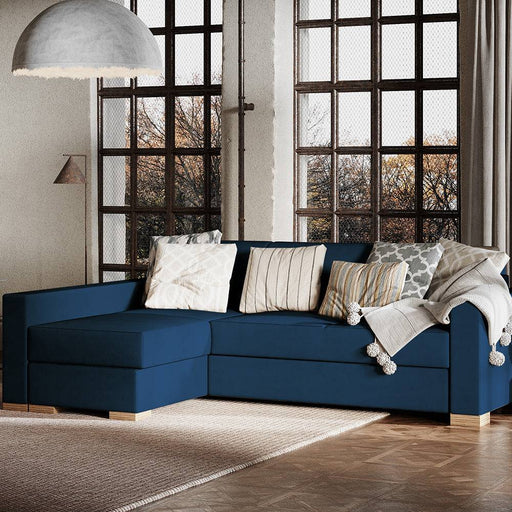 Divano letto angolare in tessuto blu scuro con cuscini decorativi beige e grigi, stile moderno, dimensioni 82x95x232 cm, ambientazione luminosa con grandi finestre