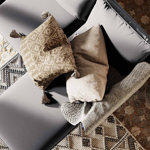 Divano angolare in tessuto grigio chiaro con cuscini decorativi beige e marroni, stile contemporaneo, perfetto per ambienti accoglienti.