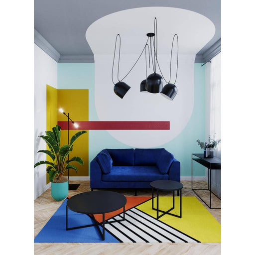 Lampada da soffitto nera con luci direzionali, installata in soggiorno colorato con divano blu, tappeti e piante, stile moderno e vivace