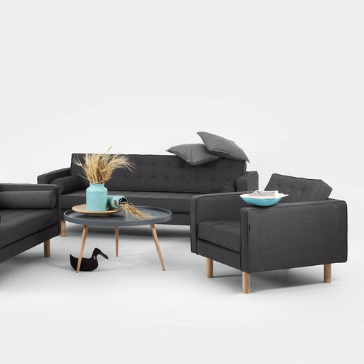 Soggiorno con divano in tessuto grigio scuro, stile contemporaneo, con tavolino rotondo e decorazioni, atmosfera accogliente e raffinata