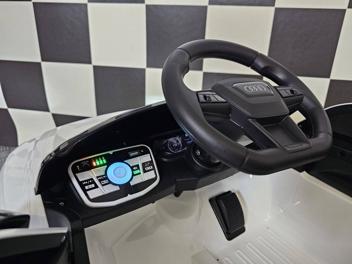 Dettaglio del volante dell'auto elettrica per bambini Audi E-Tron, con logo Audi e comandi integrati, in plastica nera con dettagli realistici