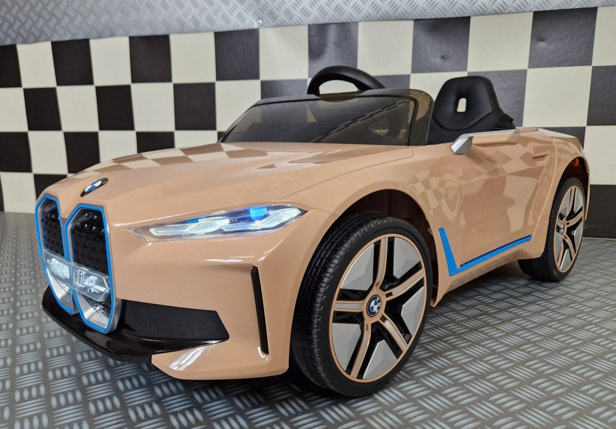 Vista frontale dell'auto elettrica per bambini BMW i4 in colore champagne con dettagli di design, luci accese e logo BMW