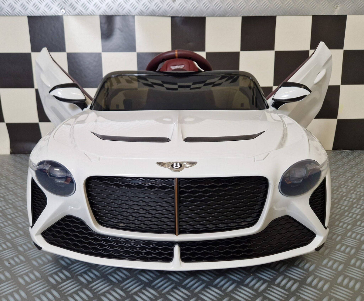 Auto elettrica per bambini Bentley Bacalar bianca con portiere aperte, dettagli in marrone e sedile rosso, luci posteriori accese, stile sportivo