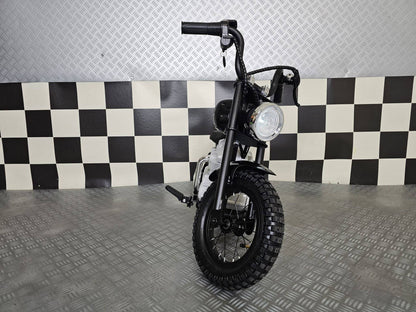 Vista frontale della moto elettrica per bambini modello chopper nero, con manubrio alto e grande faro rotondo, sedile in pelle e dettagli in stile motociclista.