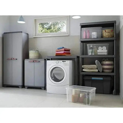 Stilo Cabinet Low in resina grigio scuro accanto a una lavatrice e scaffali, perfetto per lavanderie o garage organizzati.