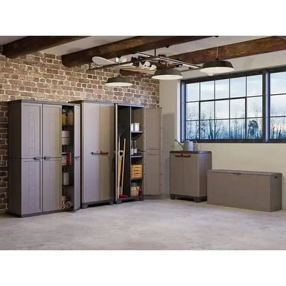 Set di mobili in resina grigio scuro, incluso Stilo Cabinet Low, in un ampio spazio con pareti in mattoni e finestre luminose.