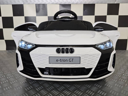 Vista laterale dell'auto elettrica per bambini Audi E-Tron bianca con portiere aperte, dettagli neri, ruote grandi e design realistico