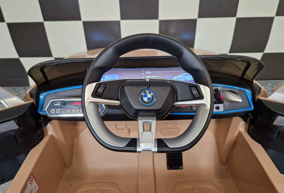 Dettaglio del volante dell'auto elettrica per bambini BMW i4, con logo BMW e comandi integrati, in colore champagne