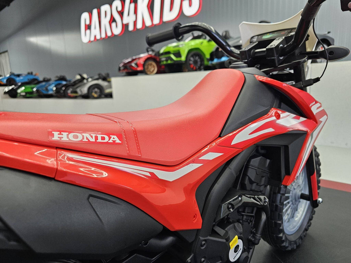 Dettaglio del sedile rosso con cuciture e logo Honda, sulla moto elettrica per bambini Honda CRF 12V, in esposizione