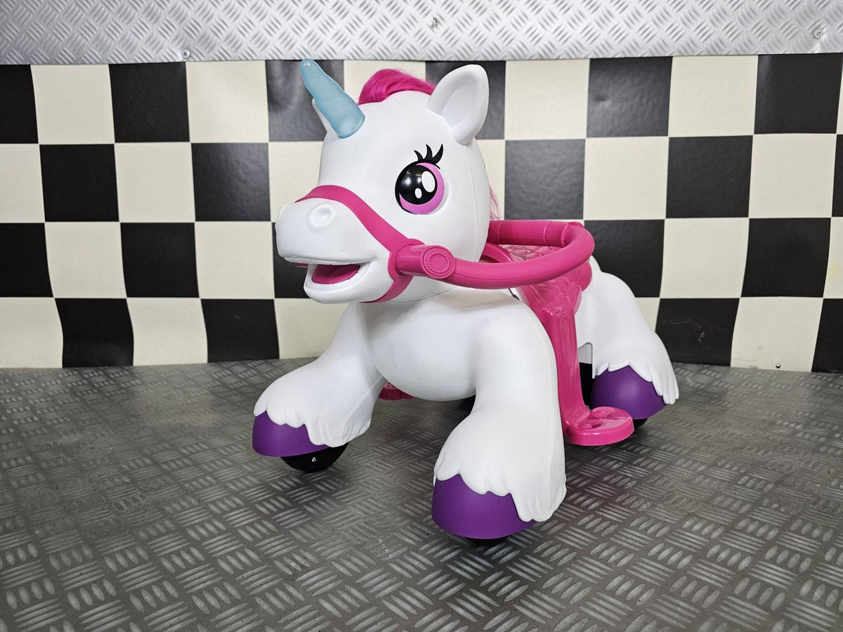 Cavallo a dondolo elettrico a forma di unicorno bianco con criniera rosa, corno blu, sella rosa e ruote nere, ideale per bambini