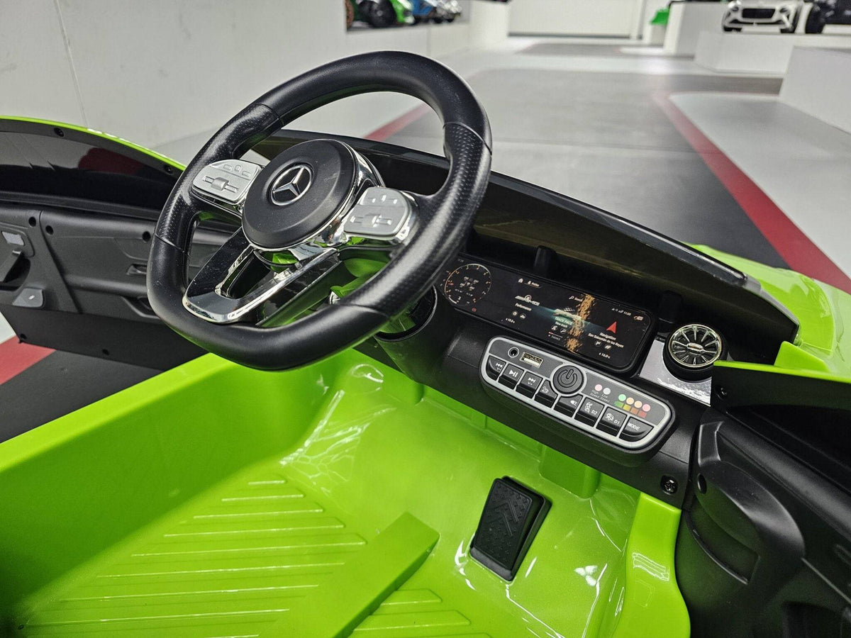 Interno dell'auto elettrica per bambini Mercedes CLA 45 con volante nero e dettagli cromati, strumentazione digitale e display centrale
