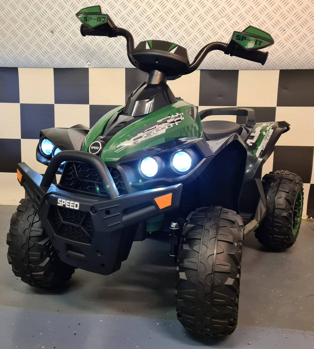 Quad elettrico per bambini con carrozzeria verde, dettagli grafici pixelati, luci anteriori blu e pneumatici grandi con battistrada robusto.