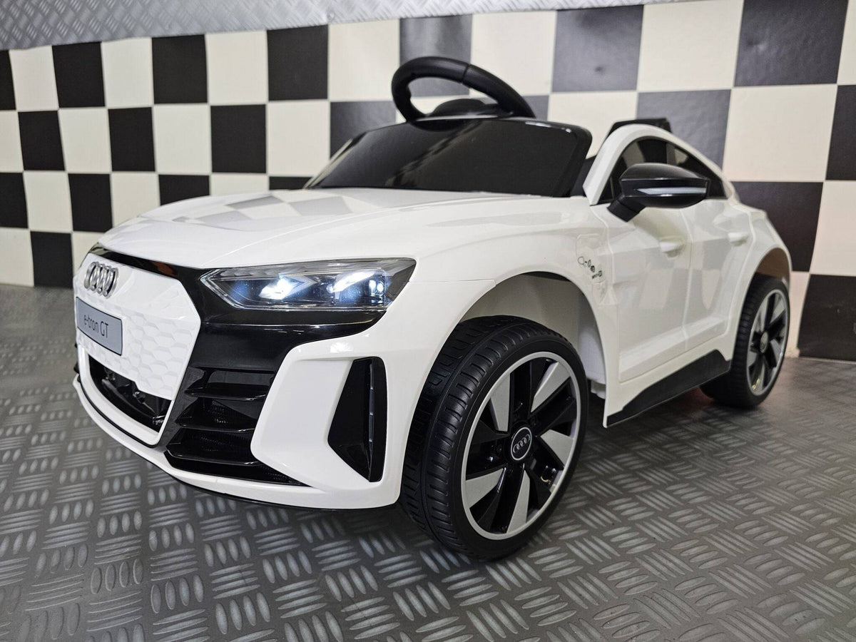 Vista frontale dell'auto per bambini Audi E-Tron bianca con fari LED accesi, dettagli neri, griglia frontale e ruote grandi in plastica