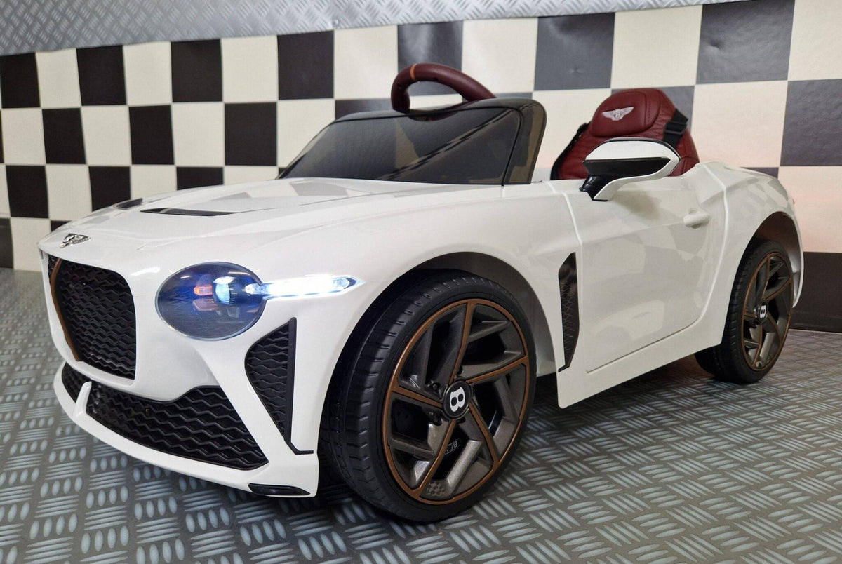 Vista dall'alto dell'auto elettrica per bambini Bentley Bacalar bianca con volante e sedile rosso, dettagli in marrone, luci posteriori accese