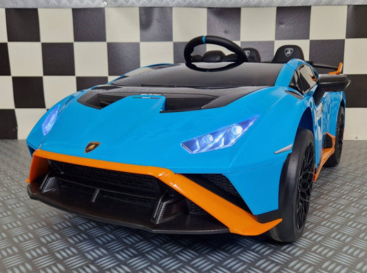 Auto elettrica per bambini Lamborghini Huracan STO blu con dettagli neri e arancioni, volante, sedili sportivi e luci LED, dimensioni compatte.