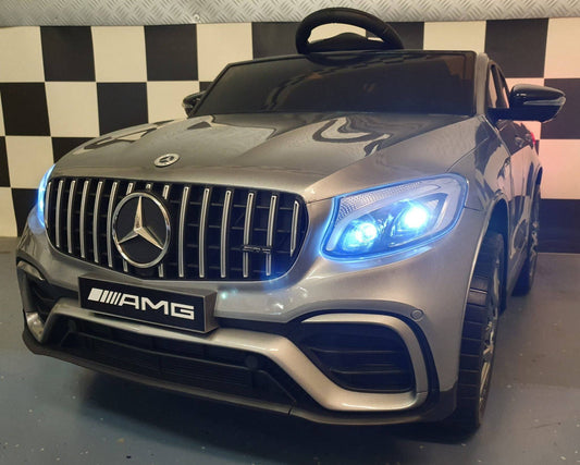 Auto elettrica per bambini Mercedes GLC 63 AMG, in grigio metallizzato con dettagli realistici, luci LED blu e ruote sportive, perfetta per gioco e divertimento