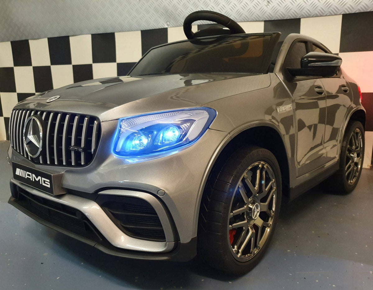 Auto elettrica per bambini Mercedes GLC 63 AMG, vista frontale con griglia e luci accese, in colore grigio metallizzato, dettagli di alta qualità