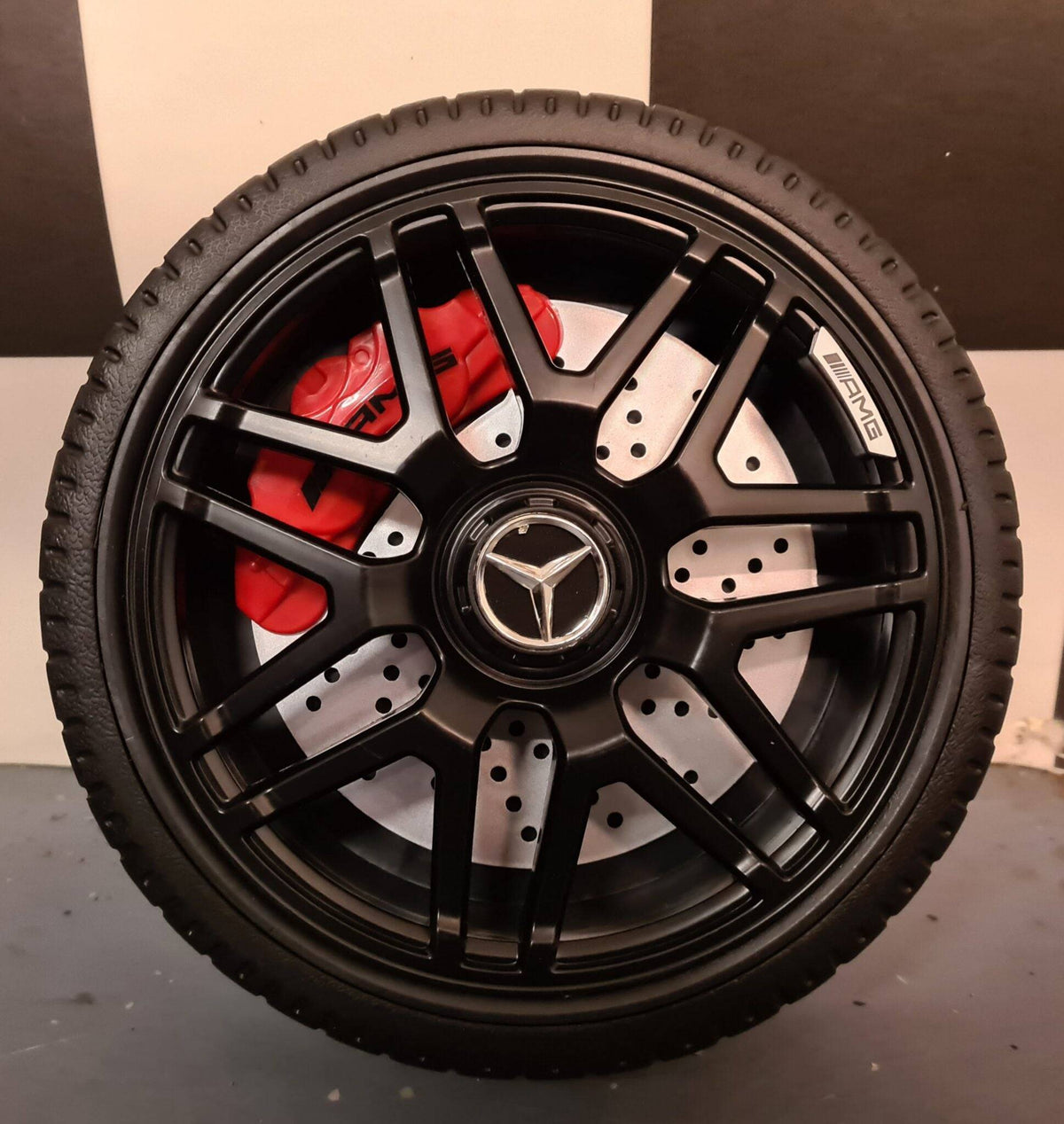 Particolare del cerchione in lega e pneumatico dell'auto elettrica per bambini Mercedes GLC 63 AMG, con dettagli realistici.