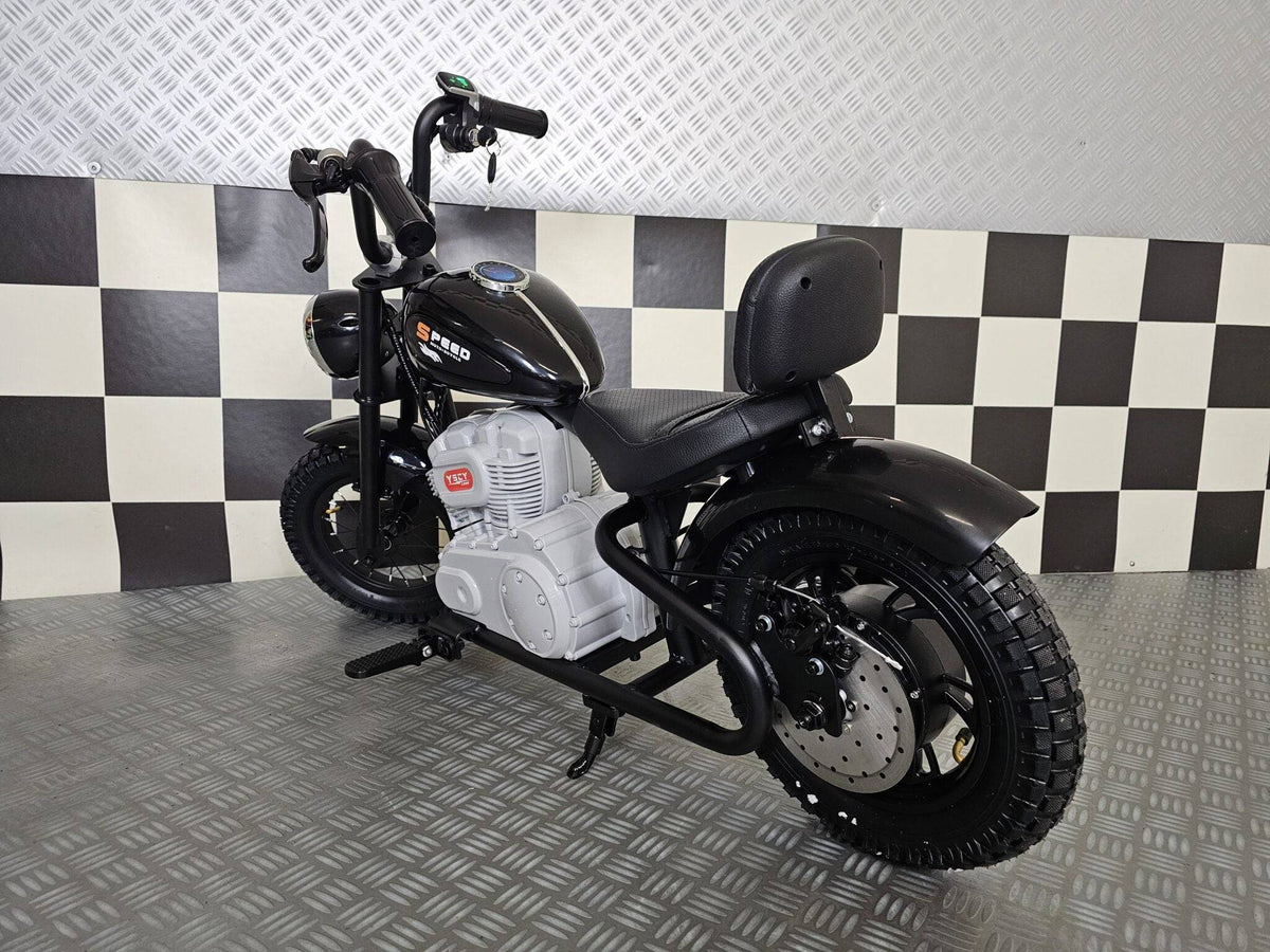 Vista frontale della moto elettrica per bambini modello chopper nero, con grande faro rotondo, manubrio alto e dettagli in stile motociclista.