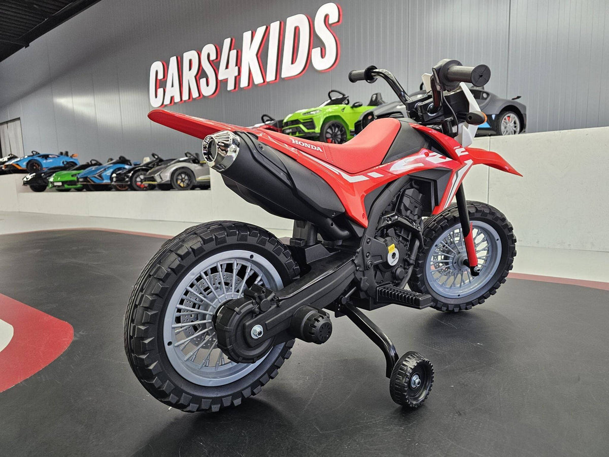 Particolare del manubrio nero con comandi e manopole, sulla moto elettrica Honda CRF 12V rossa, in esposizione in negozio