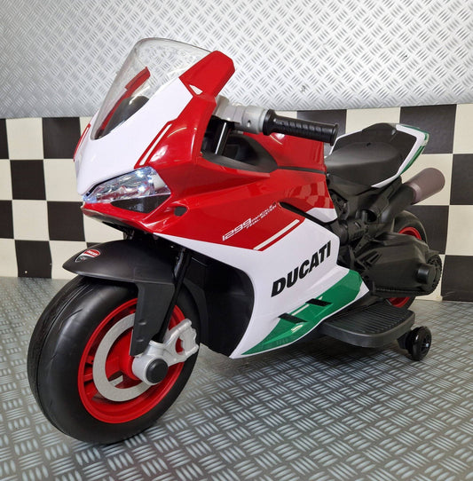 Vista frontale della moto elettrica per bambini Ducati Panigale V4 rossa, con fari LED accesi, parabrezza trasparente e dettagli italiani.