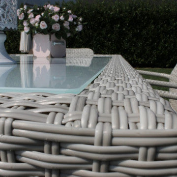 Dettaglio del bordo intrecciato in wicker del tavolo Azore grigio, con piano in vetro temperato, perfetto per esterni.
