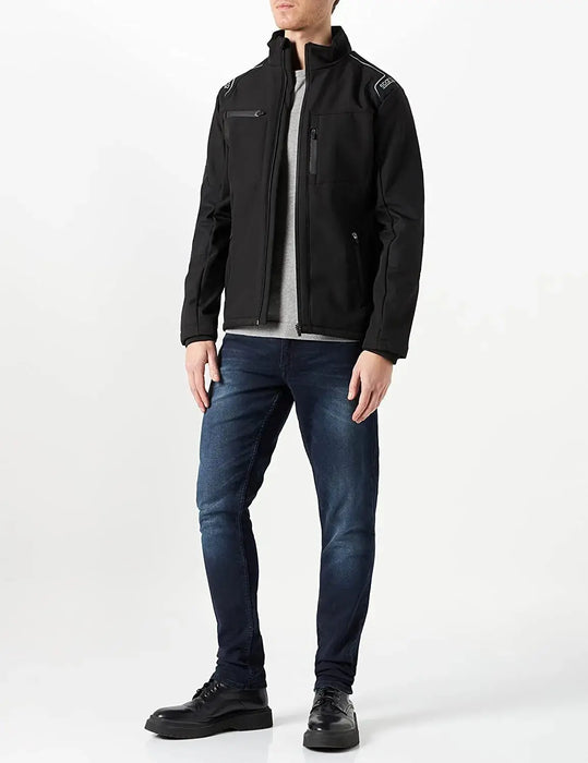 Uomo con giacca nera [Marca], maglione grigio, jeans e scarpe.