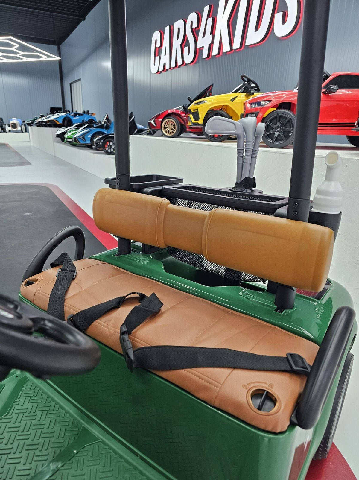 Vista frontale del carrello da golf elettrico per bambini con mazze da golf e palline nel portapenne, in un'area di gioco o esposizione