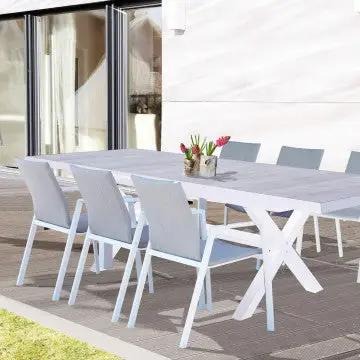 Tavolo Djerba bianco con piano in ceramica effetto legno chiaro, arredato con sedie per un ambiente esterno raffinato e moderno.