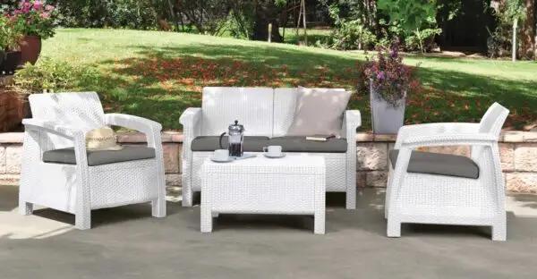 Set da giardino in polipropilene bianco con divano, due poltrone e tavolino, dotato di cuscini grigi. Design elegante e resistente per spazi esterni.