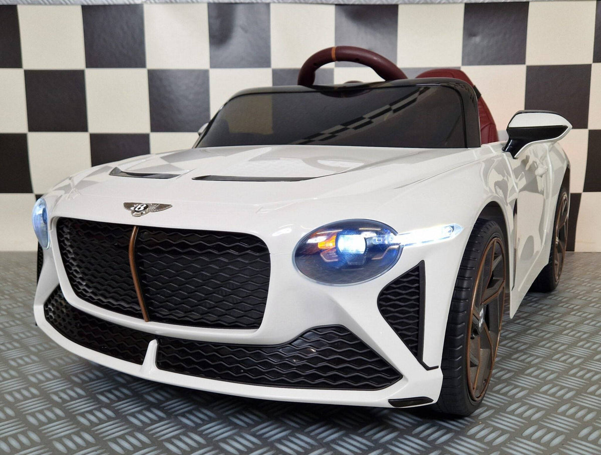 Auto elettrica per bambini Bentley Bacalar bianca con dettagli in marrone, volante e sedile rosso, luci anteriori accese, stile sportivo e realistico