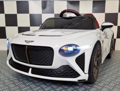 Auto elettrica per bambini Bentley Bacalar bianca con dettagli in marrone, volante e sedile rosso, luci anteriori accese, stile sportivo e realistico
