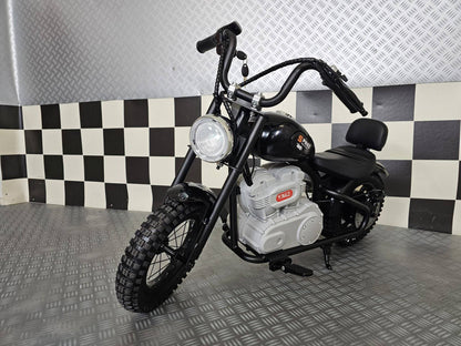 Vista laterale della moto elettrica per bambini modello chopper nero con dettagli in stile motociclista, grande ruota anteriore e motore visibile.