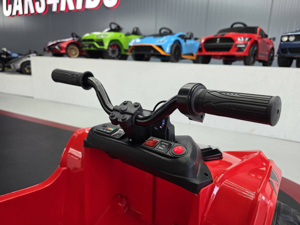 Quad elettrico per bambini rosso con dettagli neri e fari LED, in esposizione in negozio con altri veicoli giocattolo sullo sfondo