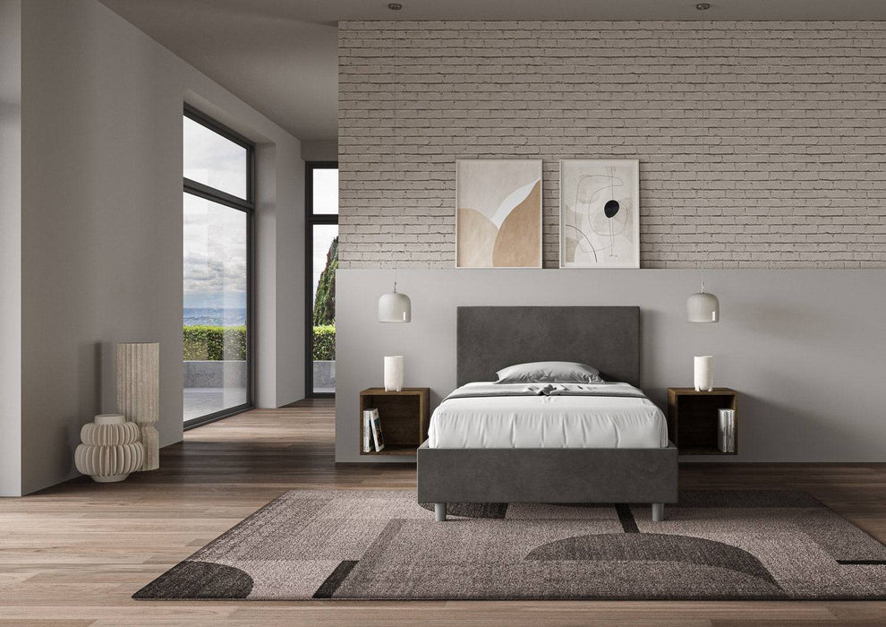Letto singolo contenitore imbottito 100x210 microfibra Adele grigio scuro in ampio ambiente luminoso, perfetto per arredamento elegante.