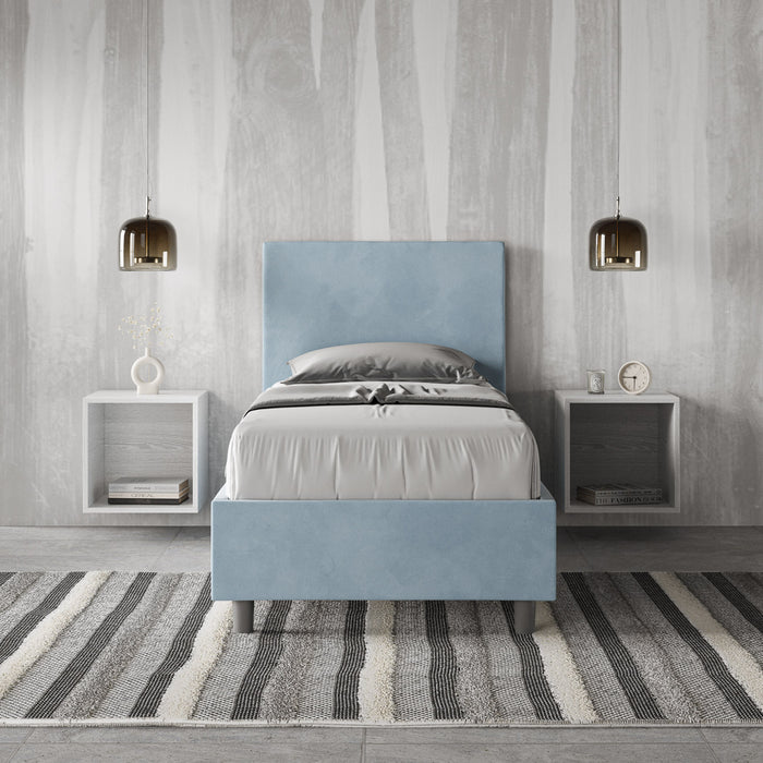 Letto singolo Adele 80x210 azzurro cielo in microfibra, ambientato in camera moderna con pareti effetto legno e tappeto a righe.