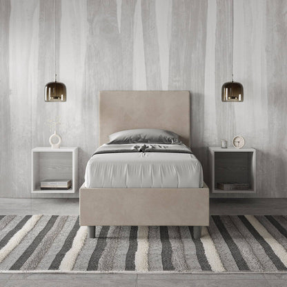 Letto singolo contenitore imbottito 90x200 microfibra Adele beige in camera moderna. Arredo raffinato con comodini sospesi e tappeto a righe.