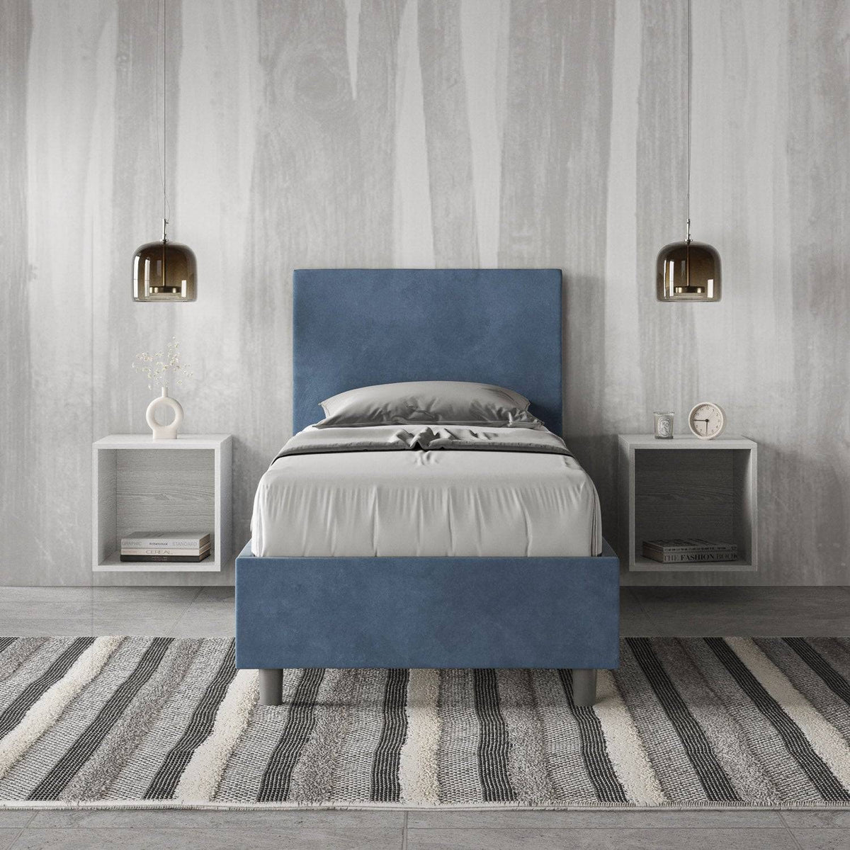 Letto singolo contenitore imbottito 90x200 microfibra Adele blu navy in camera elegante. Arredo minimal con comodini sospesi e tappeto a righe.