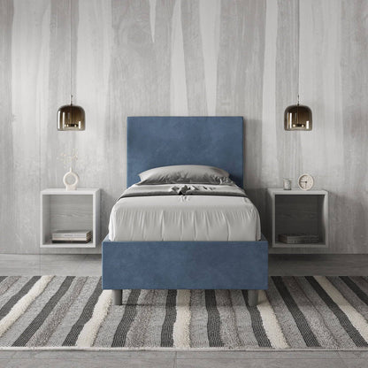 Letto singolo contenitore imbottito 90x200 microfibra Adele blu navy in camera elegante. Arredo minimal con comodini sospesi e tappeto a righe.